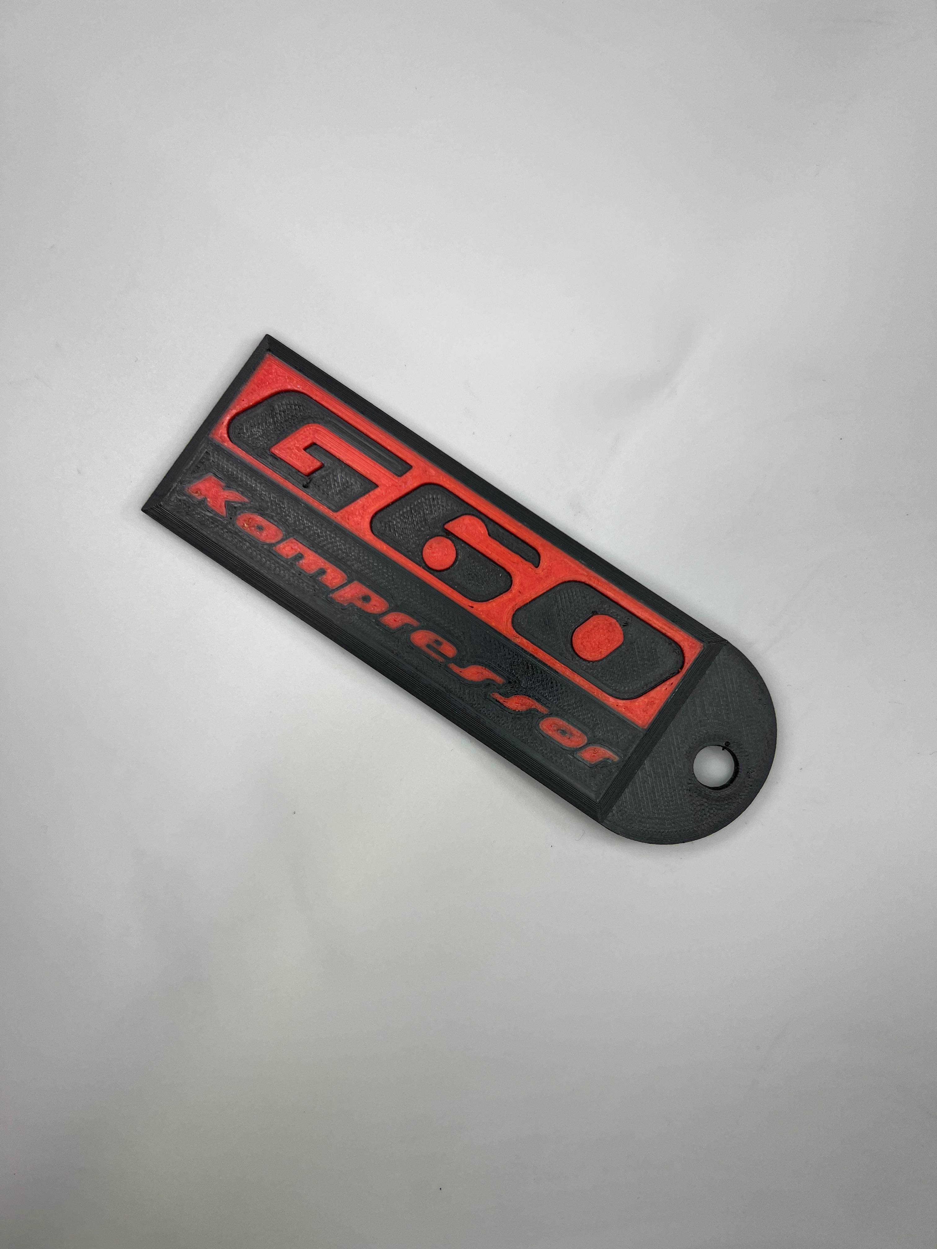 Emblem G60 Kompressor in der Farbe Rot und Schwarz aus Kunststoff
