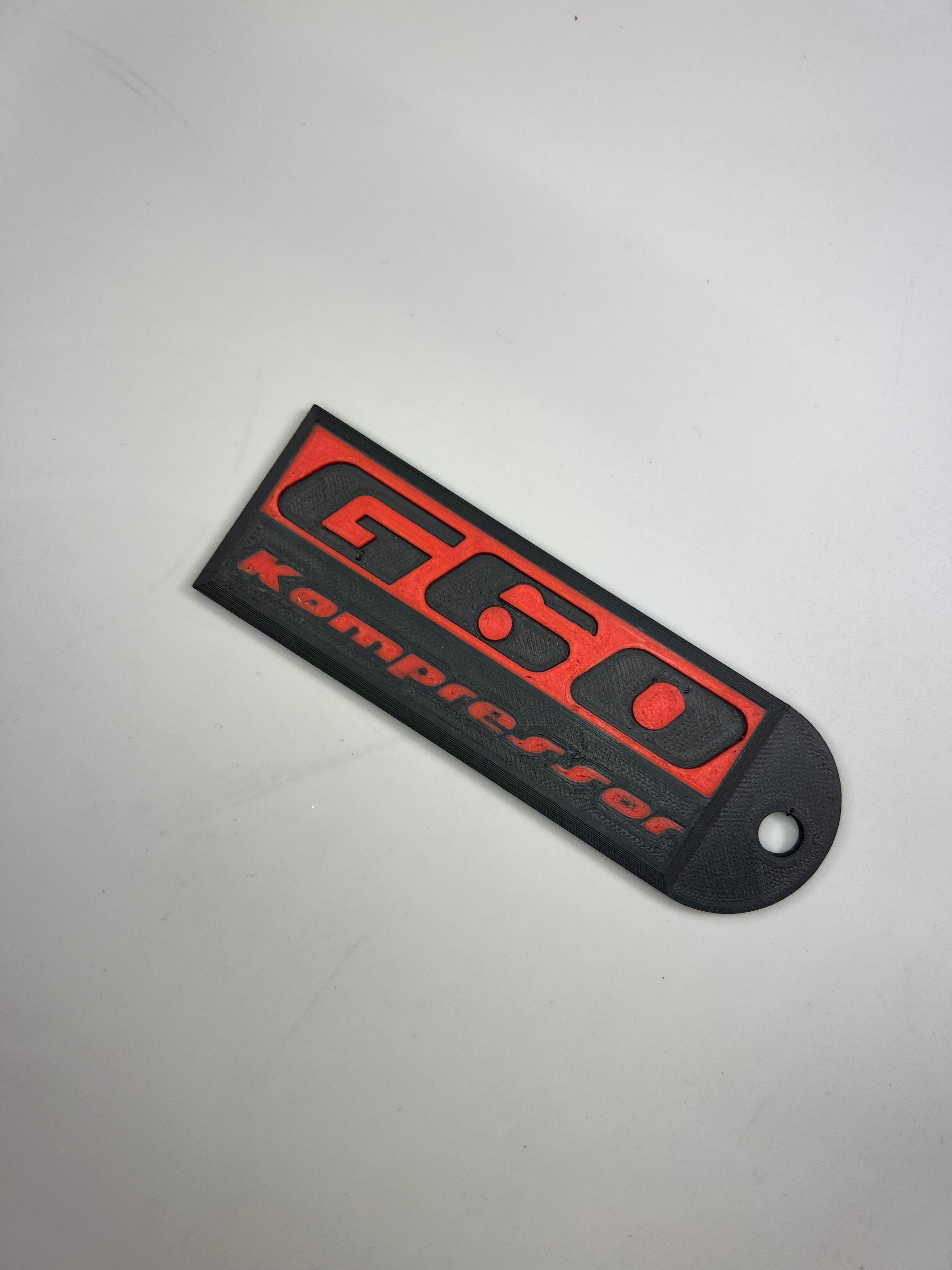 Emblem G60 Kompressor in der Farbe Rot und Schwarz aus Kunststoff