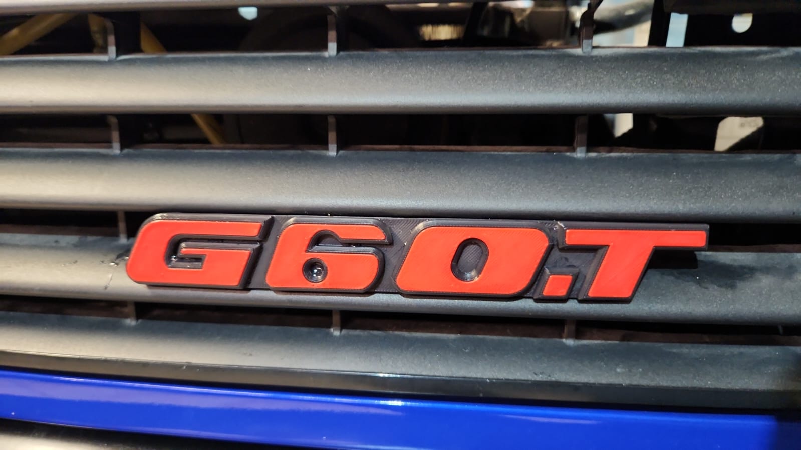 Emblem G60T  in der Farbe Rot und Schwarz aus Kunststoff für den Kühlergrill